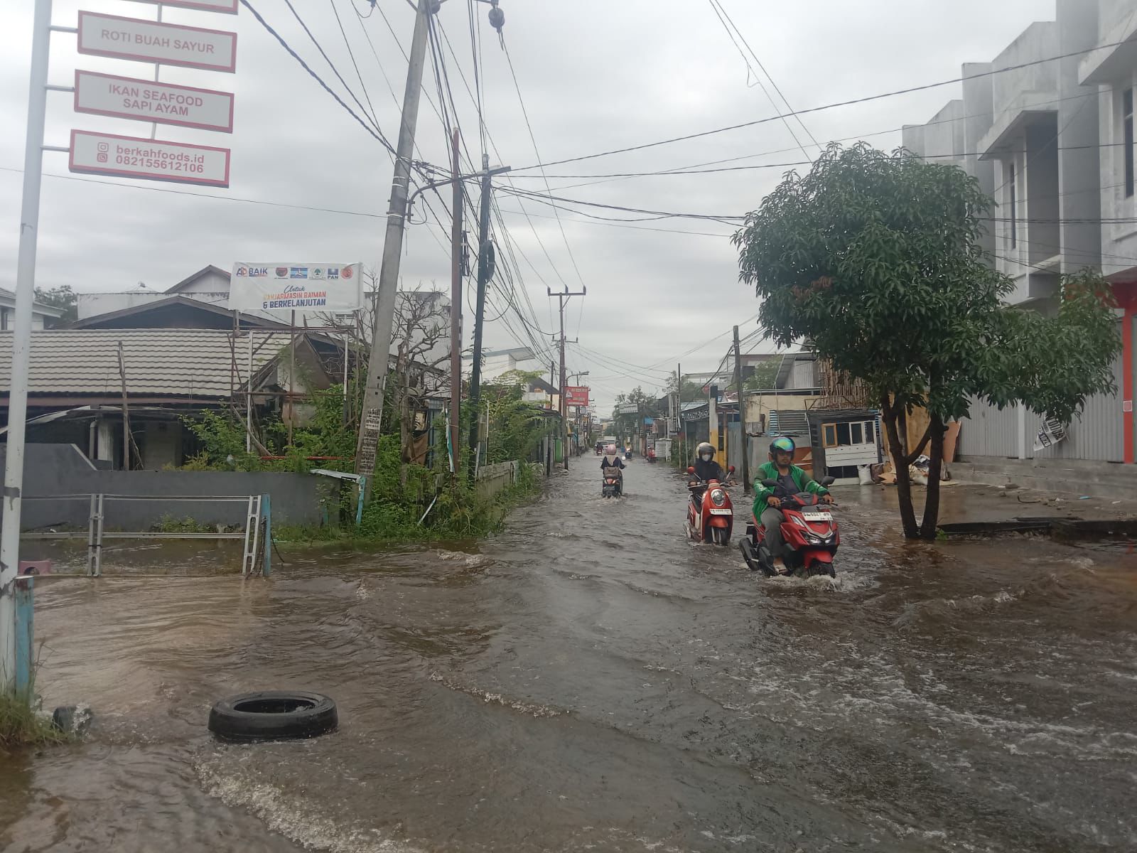 Terlihat Jalan Beruntung Jaya Banjarmasin Selatan Diserbu Banjir, namun tak menyurutkan warga tetap melintas dengan hati-hati