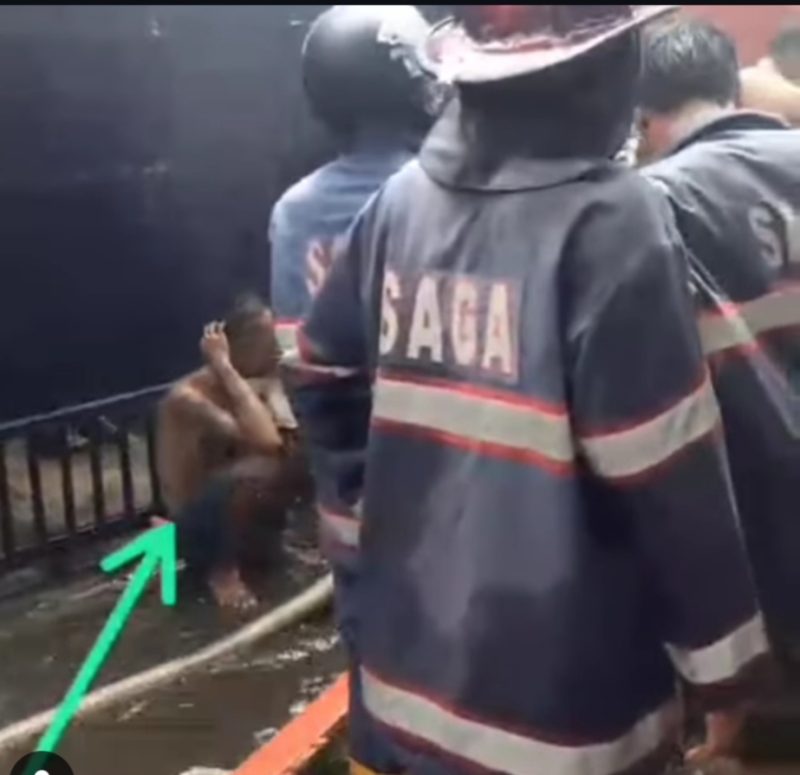 Pria (tanda panah ) asyik ngelem sementara petugas damkar sibuk melakukan pemadaman kebakaran di Jalan S Parman Banjarmasin, saat sholat Jumat (30/5/2025). (foto: tangkapan layar @kabarbanuakalsel)
