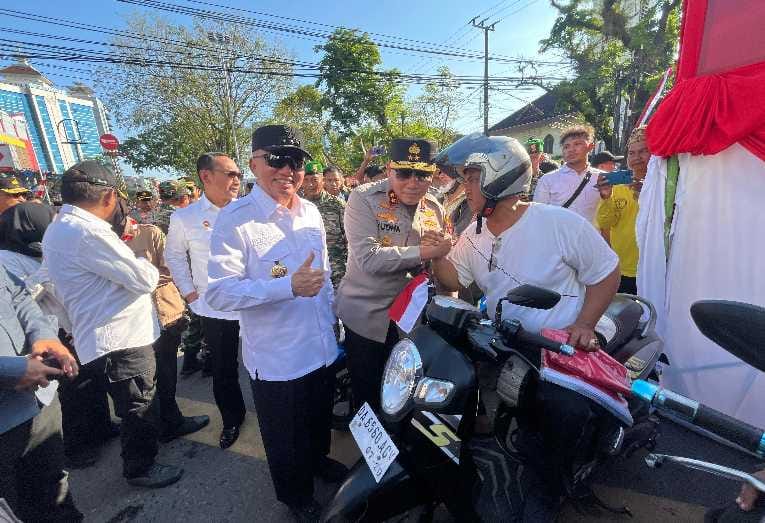 Kapolda Kalsel Irjen Pol Rosyanto Yudha Hermawan dan Gubernur Kalsel H. Muhidin saat membagikan bendera merah putih kepada pengendara motor di Jalan Lambung Mangkurat, Kamis (7/8/2025) (Foto Istimewa)