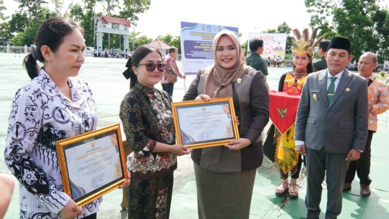 Wakil Ketua I DPRD Murung Raya Dina Maulidah, S.HI saat menyerahkan piagam penghargaan pada upacara peringatan Hari Otda ke-XXX dan Hardiknas (foto: Maya)