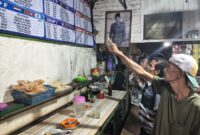 ANTUSIAS PIALA DUNIA – Sejumlah pelanggan Warung Kai Adi di Jalan Kolonel Sugiono/Pekapuran B, Banjarmasin Tengah, antusias mengamati jadwal pertandingan Piala Dunia yang terpampang di warung tersebut. Suasana diskusi dan prediksi antarpendukung tim favorit mulai ramai mewarnai warung-warung kopi menjelang bergulirnya turnamen sepak bola terbesar di dunia. (foto:Mercy )
