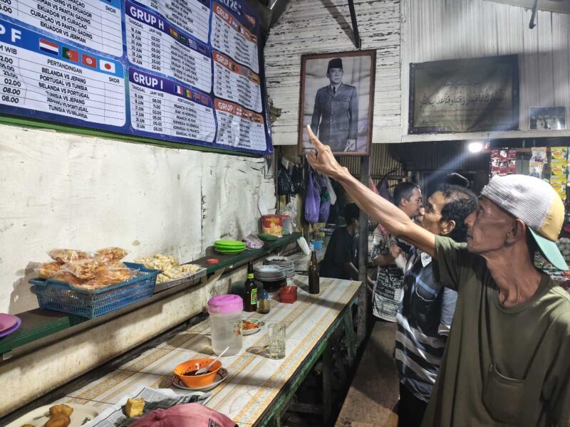 ANTUSIAS PIALA DUNIA – Sejumlah pelanggan Warung Kai Adi di Jalan Kolonel Sugiono/Pekapuran B, Banjarmasin Tengah, antusias mengamati jadwal pertandingan Piala Dunia yang terpampang di warung tersebut. Suasana diskusi dan prediksi antarpendukung tim favorit mulai ramai mewarnai warung-warung kopi menjelang bergulirnya turnamen sepak bola terbesar di dunia. (foto:Mercy )
